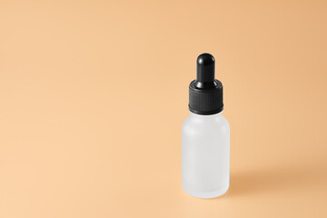 A glass bottle with a pipette containing a cosmetic product. beige background. Copy space.
