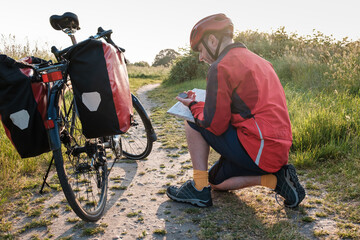 Cyclist squatting on floor reading compass and map.