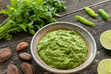 Coriander chutney and main ingredients: bunch of cilantro leaves, green chilies, lime and Brazil nuts.