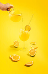Añadiendo bebida de limón o limonada, en un vaso/copa. Con limones cortados como decoración. 