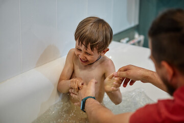 Father and child have fun in the bathroom while bathing son