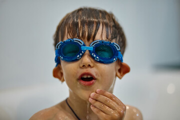 Child in diving goggles have fun while bathing in the bathroom