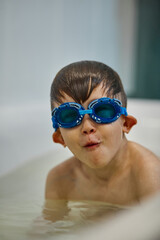 Child in diving goggles have fun while bathing in the bathroom