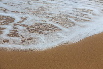 Fototapeta na wymiar Sea foam on the sandy beach