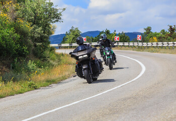 Fototapeta na wymiar Two motorcyclists on motorcycles ride on a winding road