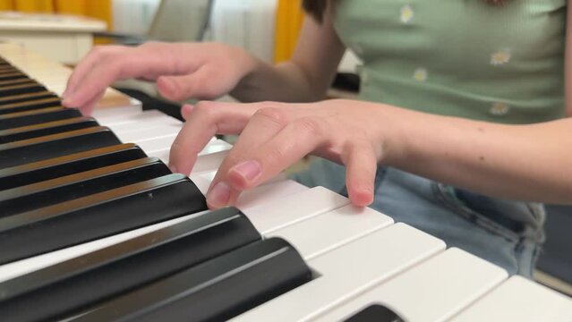 a little girl playing the piano at home, a girl playing a musical instrument, the hands of a child playing the piano close-up