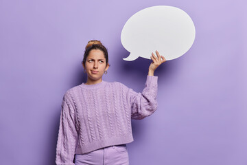 Unhappy sulking young European woman holds communication bubble for your advertisement wears casual...