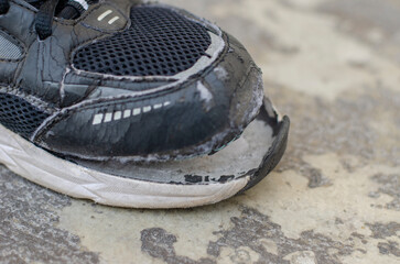 Fototapeta na wymiar closeup view broken old black sneakers on the floor