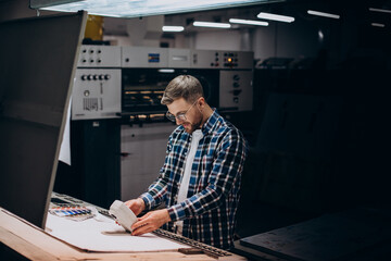 Man working in printing house with paper and paints