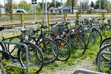 Classic black bikes are parked in the bike parking lot. Bicycles stand near the railway station.