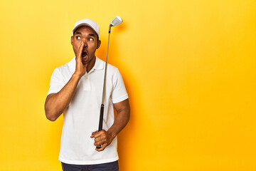 Naklejka premium African American man golfer, yellow studio backdrop, is saying a secret hot braking news and looking aside