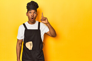African American cook with utensils, yellow studio, having an idea, inspiration concept.