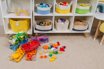 Colorful rainbow colored constructor pieces in transparent plastic boxes in childrens room. Bright stackable plastic toy bricks sorting by colors. Space organizing at childrens room.