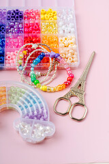 Kids handmade beaded jewelry and different multi-colored beads for children's needlework and crafts in boxes. DIY art activity for kids. Motor skills, creativity and  hobby.