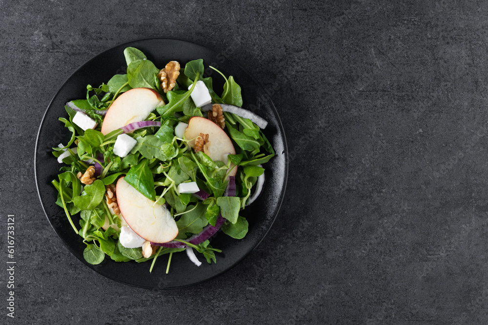 Wall mural Autumn salad with apples and walnuts on black slate background. Top view. Copy space