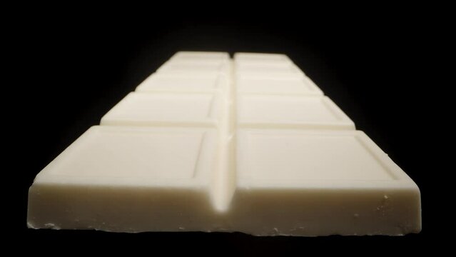 A white chocolate bar on a black background for cutout. Light illuminates it from different angles. Close-up.