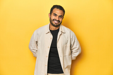 Obraz premium Casual young Latino man against a vibrant yellow studio background, happy, smiling and cheerful.