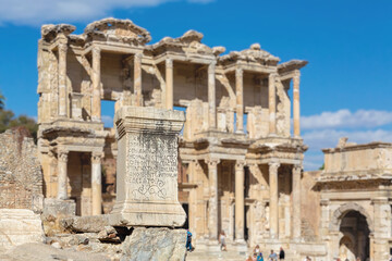 Fototapeta premium Celsus Library and stone with Ancient Greek inscription (Ancient law in greek language). Scenic view on magnificient ruins of the ancient city of Ephesus. Selcuk (Izmir region). Turkey