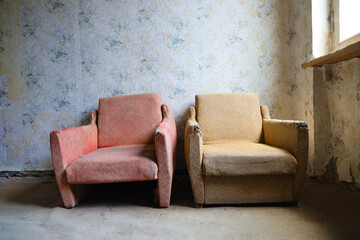 two abandoned retro aged armchair standing near window. old vintage living room.