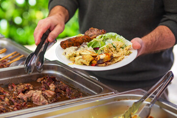 A man with a barbecue plate at a party between friends. Food, people and family time concept.