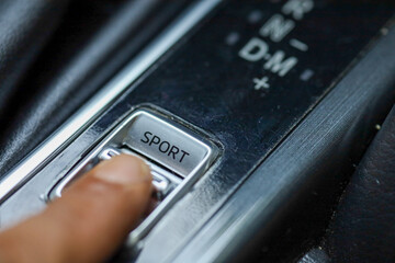 Close up on the Sport Mode button of a car. Finger pressing the button.
