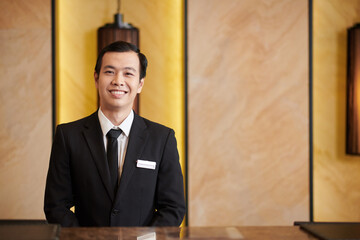 Portrait of positive Asian hotel receptionist with badge on his suit