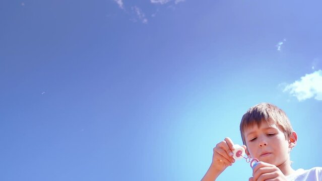 Bubble Bliss: A Boy Blowing Soap Bubbles against the Blue Sky, Slow Motion, have fun