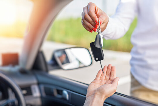 A woman's hand passes the key to the car. Buying a car or renting.
