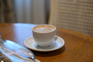 Hot Coffee in white cup on wooden table in kitchen room at comfort home.