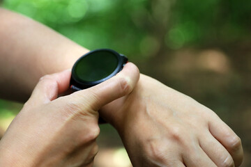 Smart watch on female hand in summer park. Round display with apps for hiking and sports training