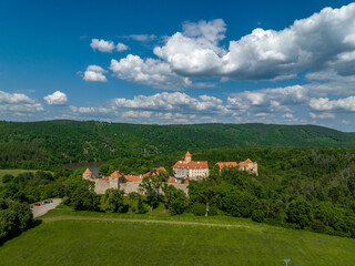 Fototapeta na wymiar Aerial view of Veveri castle in Moravia with large courtyards, multiple gates, square and round towers with cloudy blue sky 