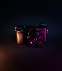 Photo camera on dark background. Neon lights. Photo gear copy space.
