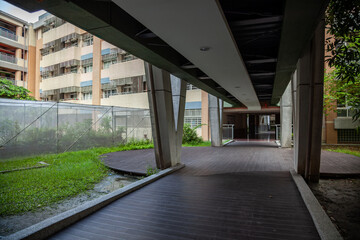 A modern passage to the rest of the building in the atrium with a wooden floor, surrounded by green grass and windows
