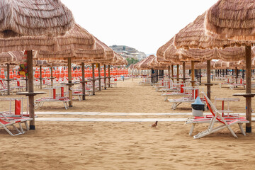 brown umbrellas and red sunbeds in pescara, italy