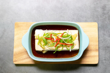 Vegan silken tofu is served hot or cold with a savory soy sauce flavored with sesame oil, ginger and green onions .