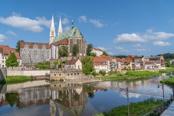 Fototapeta na wymiar Pfarrkirche St. Peter und Paul Landmark Gothic evangelical church noted for its soaring twin spires, copper roof in Gorlitz Germany reflecting off the Niesse river