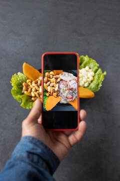 Man takes a photo on his smartphone Peruvian ceviche dish of marinated fish, food blog.