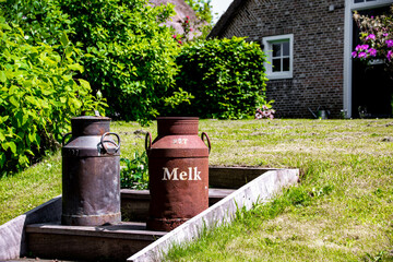 Old milk cans by a country house by the canal