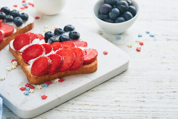 4th of July American Independence Day food. American flag sandwich with strawberries, blueberries, whipped sweet cream, soft cheese on toast bread. Independence or Patriotic Day breakfast idea Mock up