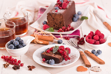 Chocolate sponge cake with fresh fruit on white dish. - 616769385