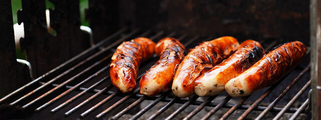 Cooking food in garden. On BBQ grill grate are fresh grilled traditional Nuremberg sausages, ready...