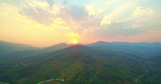 .Beautiful sunset on the hill amid the mountain range with the setting sun in Chiang Rai..Sunbursts flashed in the mountains range in beautiful sunset..Majestic sunset or sunrise landscape.