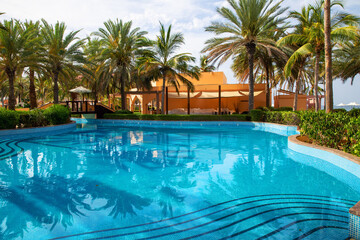Fototapeta na wymiar Swimming pool with clear water surrounded by palm trees in one of the best resorts