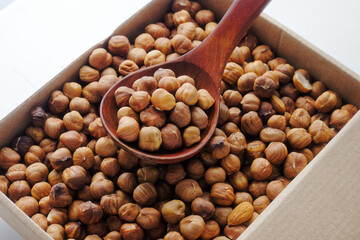 Box with peeled hazelnuts. View from above. Delivery of healthy nuts in a cardboard box. A pile of hazelnuts in a wooden spoon.