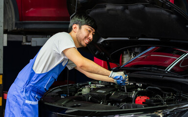 Naklejka na ściany i meble Portrait Adult Professional handsome male mechanic wearing uniform, fix, repair, check, inspect car engine, standing in automobile maintenance service center or shop.