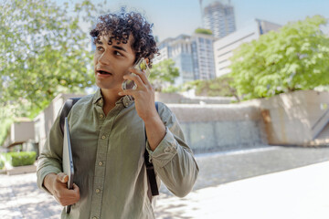 Portrait of smiling handsome hispanic student talking on mobile phone