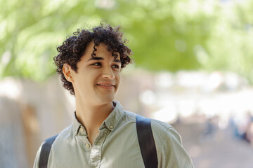 Smiling handsome hispanic student looking away outdoors