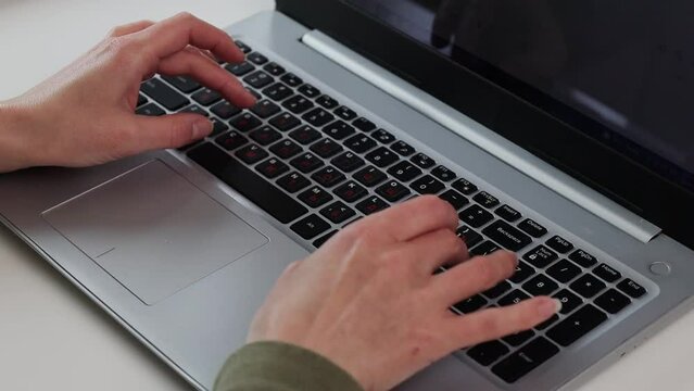 Female hands typing on a laptop at a white table