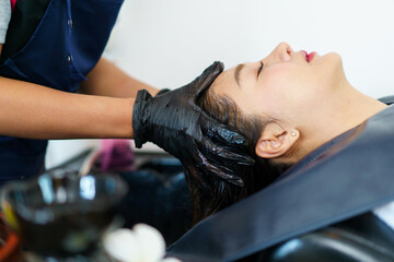 Close up shoot of Asian beautiful woman get hair washing and caring at professional salon shop.