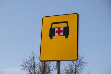 Road sign that shows way for ambulance. Ambulance yellow street sign on sky background